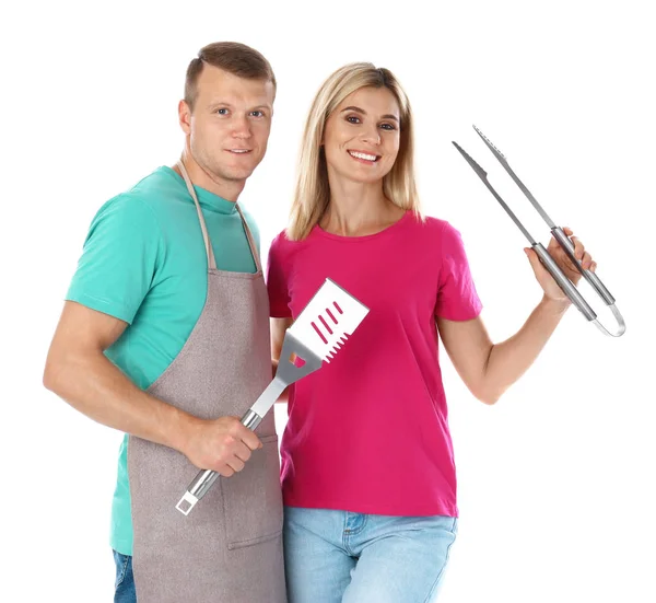 Casal feliz com utensílios de churrasco no fundo branco — Fotografia de Stock