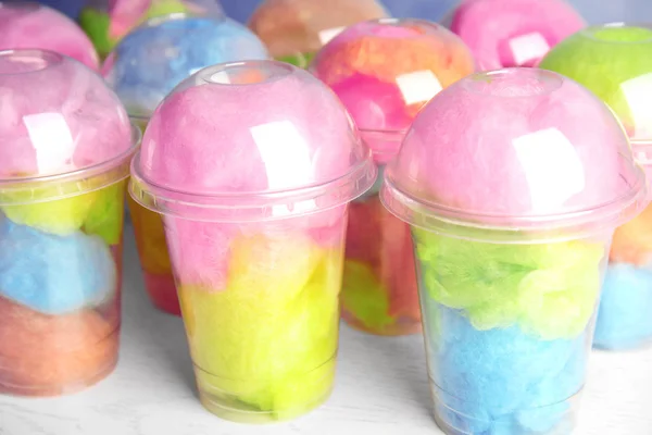 Many plastic cups with tasty cotton candies on white wooden table — Stock Photo, Image