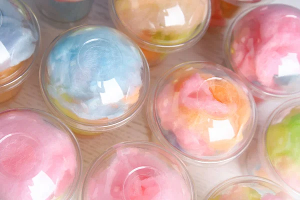 Muitas xícaras de plástico com doces de algodão saborosos na mesa de madeira branca, vista acima — Fotografia de Stock