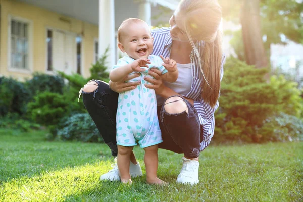 Teen nounou avec mignon bébé sur herbe verte à l'extérieur — Photo