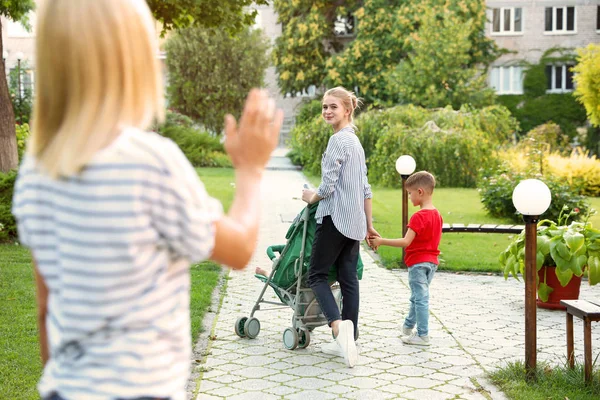 Matka pozostawiając dzieci z nastolatków Niania w Park — Zdjęcie stockowe