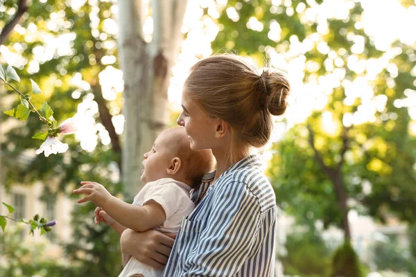 Teen Nanny med söt baby i parken på solig dag — Stockfoto