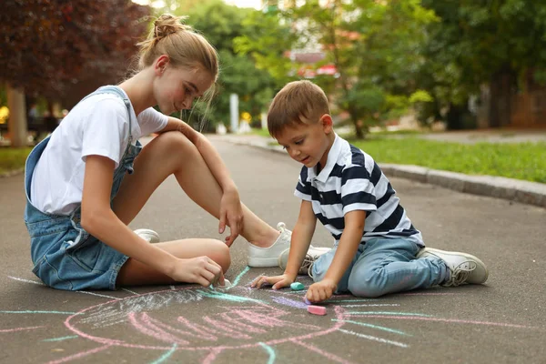 Teenie-Kindermädchen und süßer kleiner Junge zeichnen Sonne mit Kreide auf Asphalt — Stockfoto