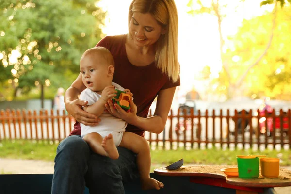 Nanny en schattige kleine baby spelen met speelgoed buitenshuis — Stockfoto