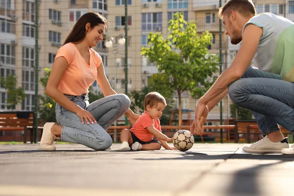Família feliz com adorável pequeno bebê jogando futebol ao ar livre — Fotografia de Stock