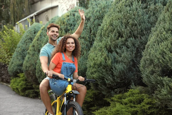 Feliz joven pareja montando bicicleta en la calle de la ciudad — Foto de Stock