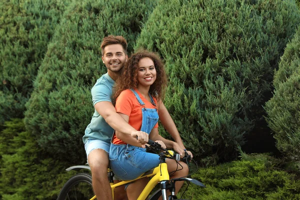 Feliz joven pareja montando bicicleta en la calle de la ciudad — Foto de Stock
