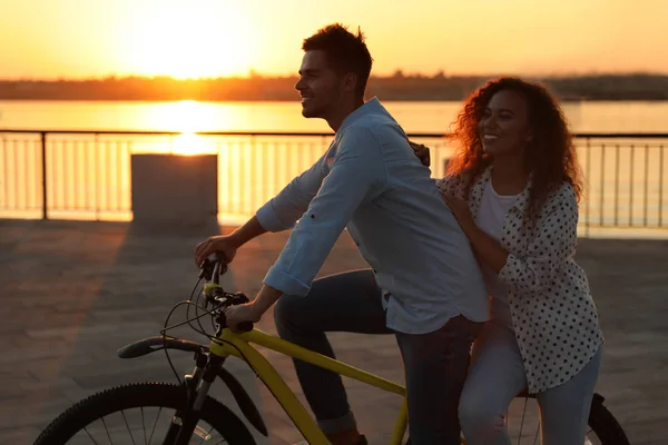 Jeune couple à vélo sur le front de mer de la ville au coucher du soleil — Photo
