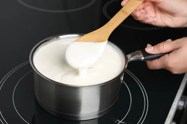 Femme cuisine délicieuse sauce crémeuse dans une casserole sur la cuisinière, gros plan — Photo