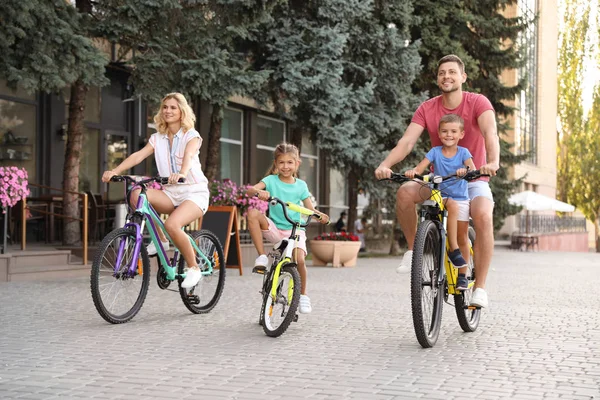 Famille heureuse avec enfants chevauchant des vélos en ville — Photo