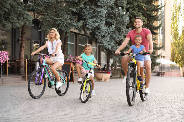 Happy family with children riding bicycles in city