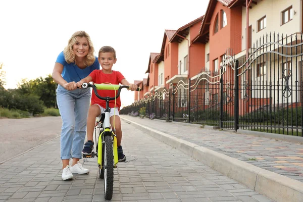 Mère heureuse enseignant à son fils à faire du vélo en ville — Photo