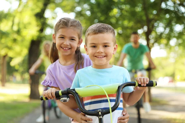 Szczęśliwe rodzeństwo i ich rodzice jeżdżą rowerami w parku — Zdjęcie stockowe