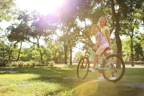 Mère heureuse enseignant à sa fille à faire du vélo dans le parc — Photo