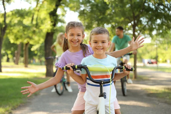 Heureux frères et sœurs et leurs parents faisant du vélo dans le parc — Photo