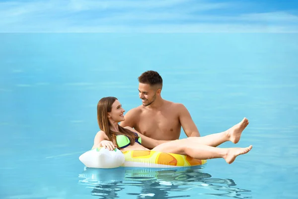 Mulher feliz em biquíni flutuando no anel inflável e seu namorado no mar. Casal encantador — Fotografia de Stock