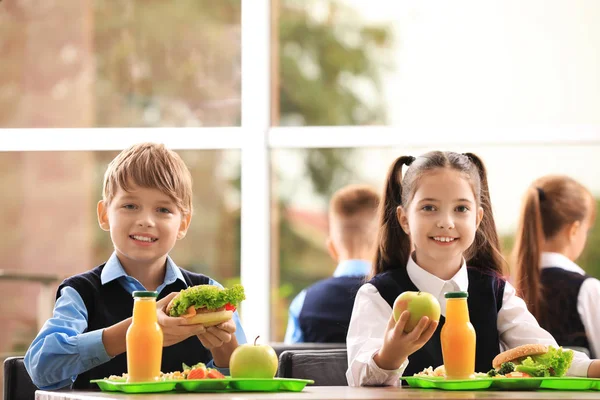 Happy children at table with healthy food in school canteen — Stock Photo, Image