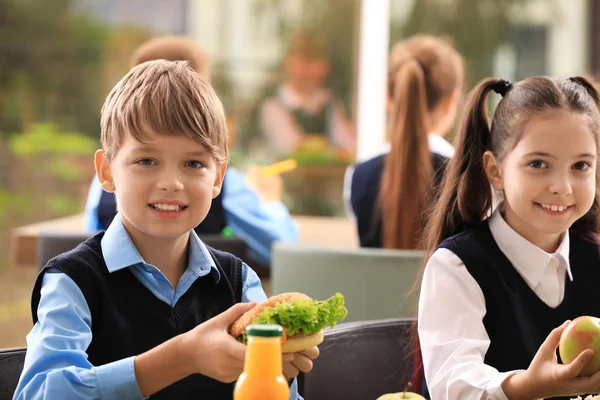 Ευτυχισμένα παιδιά στο τραπέζι με υγιεινά φαγητά στο σχολικό κυλικείο — Φωτογραφία Αρχείου