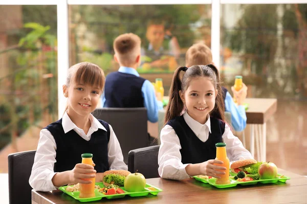 Meninas felizes à mesa com comida saudável na cantina da escola — Fotografia de Stock