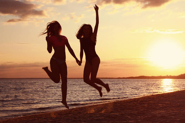 Young woman in bikini with girlfriend on beach. Lovely couple