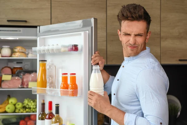 Hombre tomando botella con leche vieja de la nevera en la cocina — Foto de Stock