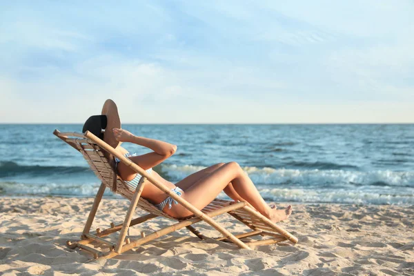 Ung kvinna koppla av i solstol på stranden — Stockfoto