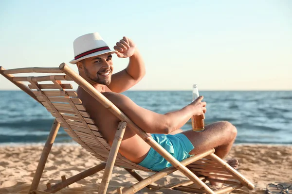 Giovane uomo rilassante sulla sedia a sdraio sulla spiaggia vicino al mare — Foto Stock