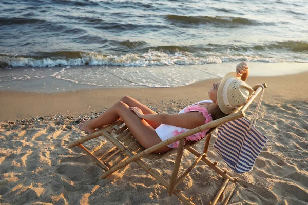 Jeune femme se détendre dans une chaise longue sur la plage — Photo