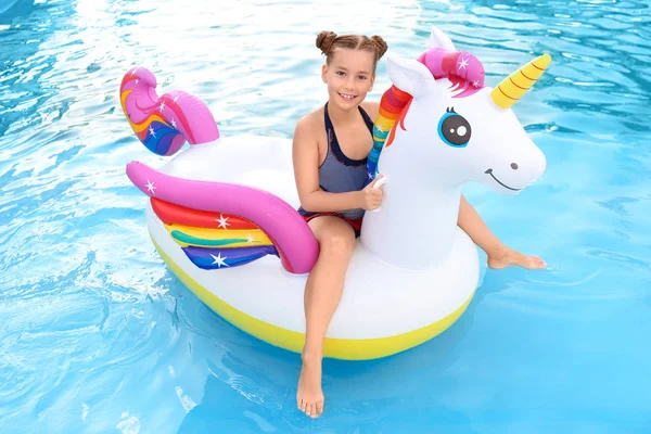 Bonne petite fille sur licorne gonflable dans la piscine — Photo