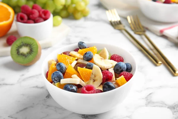 Frischer, schmackhafter Obstsalat auf weißem Marmortisch — Stockfoto