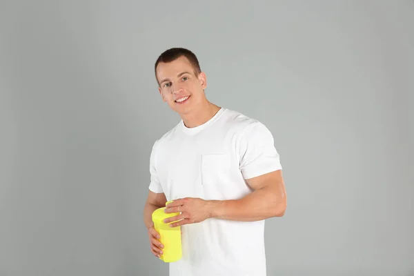 밝은 회색 배경에 단백질 쉐이크를 가진 운동 젊은 남자 — 스톡 사진