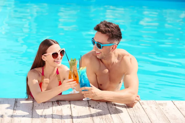 Cuplu tânăr fericit cu cocktail-uri în piscină — Fotografie, imagine de stoc