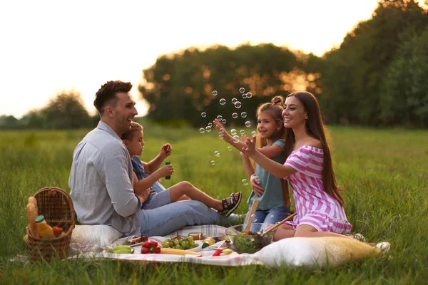 Happy family having picnic in park at sunset — Stock Photo, Image