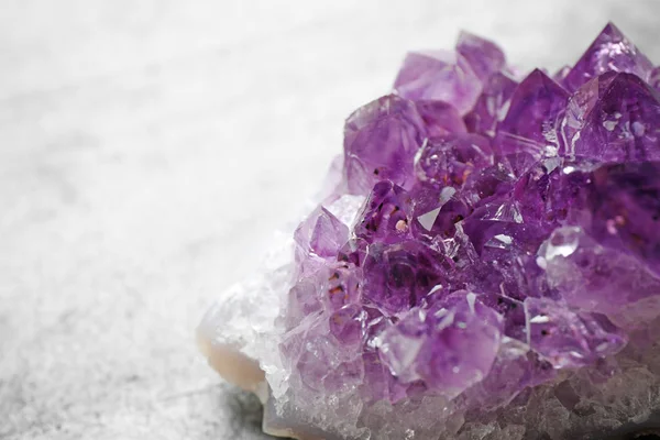 Beautiful purple amethyst gemstone on grey table, closeup view. Space for text — Stock Photo, Image