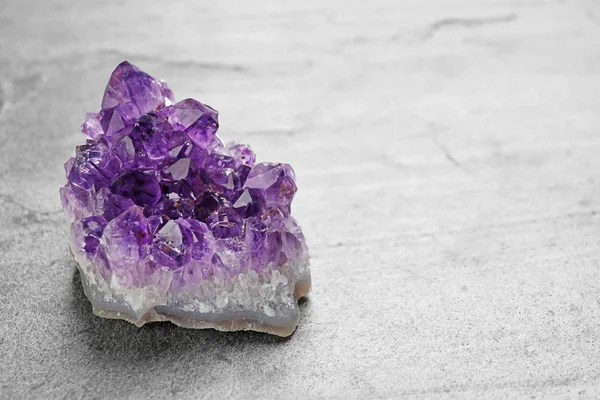 Beautiful purple amethyst gemstone on grey table, space for text — Stock Photo, Image