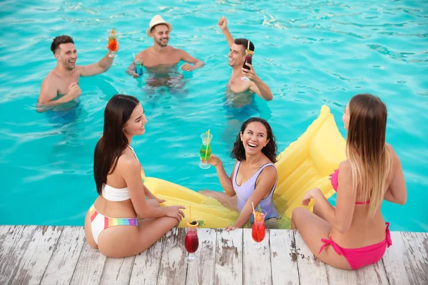 Felices jóvenes amigos con refrescantes cócteles disfrutando de la fiesta en la piscina — Foto de Stock