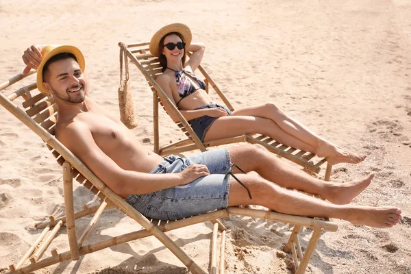 Pareja joven relajándose en tumbonas en la playa — Foto de Stock