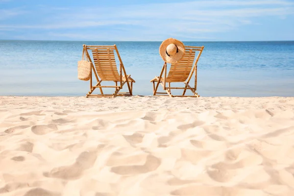 Trä däck stolar på sandstrand nära havet — Stockfoto