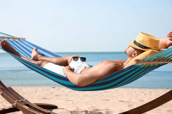 Hombre joven relajándose en hamaca en la playa — Foto de Stock