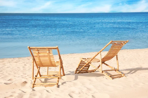 Cadeiras de madeira na praia de areia perto do mar — Fotografia de Stock