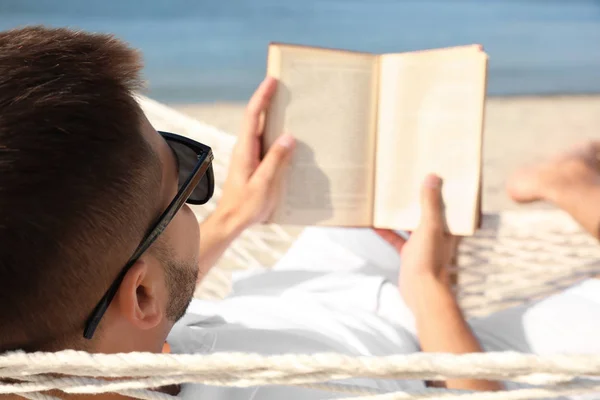 Jeune homme lisant le livre dans l'hamac sur la plage — Photo