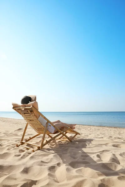 Giovane donna rilassante sulla sedia a sdraio sulla spiaggia di sabbia — Foto Stock