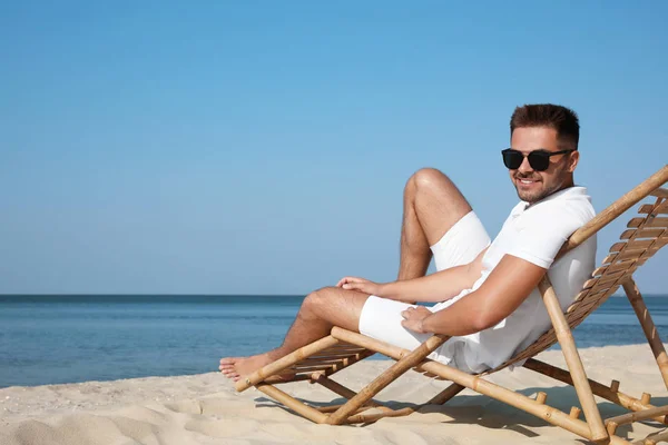 Молодий чоловік розслабляється в стільці на піщаному пляжі — стокове фото