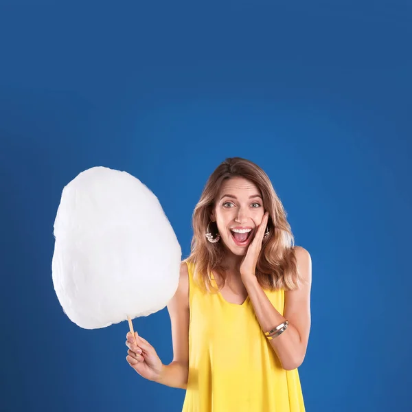 Mujer emocional con algodón de azúcar sobre fondo azul — Foto de Stock