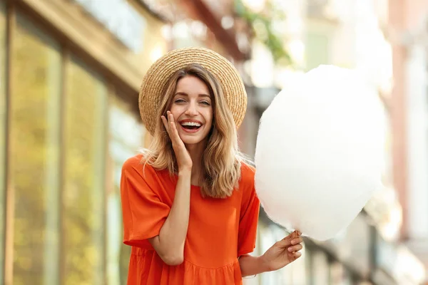 Mujer joven emocional con algodón de azúcar al aire libre — Foto de Stock