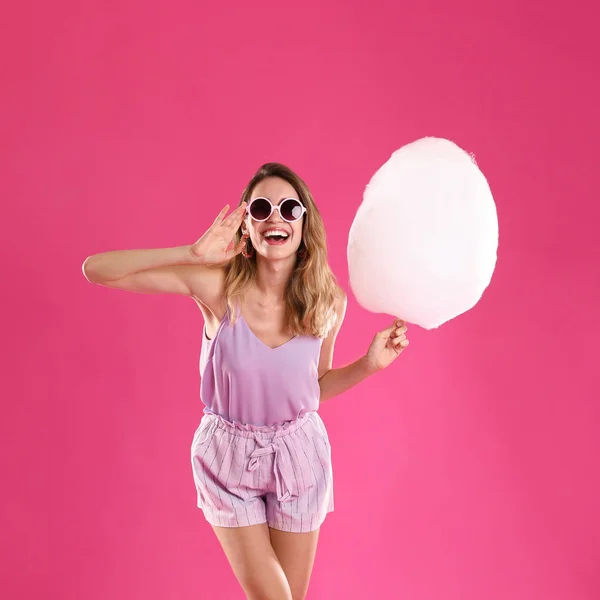 Mujer joven feliz con algodón de azúcar sobre fondo rosa — Foto de Stock