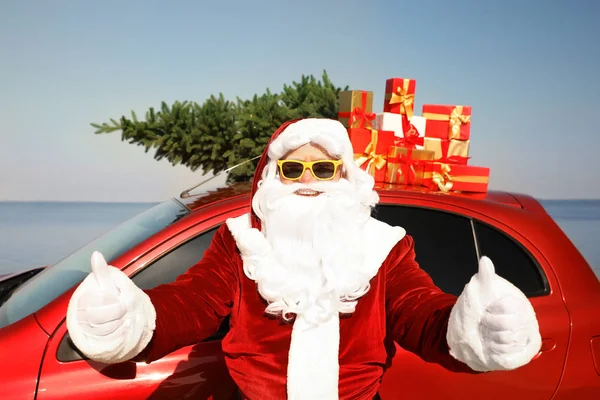 Autentico Babbo Natale vicino auto con regali e abete sul tetto in mare — Foto Stock