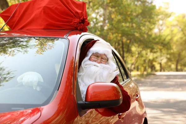 Autentico Babbo Natale con borsa piena di regali sul tetto guida auto moderne, all'aperto — Foto Stock