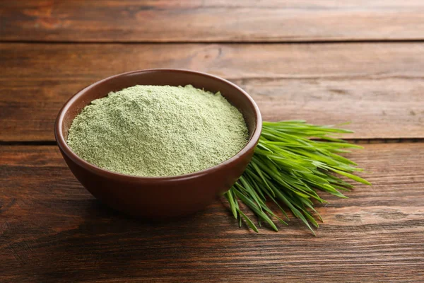 Bowl of wheat grass powder and sprouts on wooden table