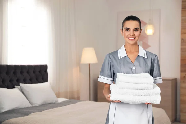 Καμαριέρα με στοίβα από καθαρές πετσέτες στο δωμάτιο του ξενοδοχείου. Χώρος για κείμενο — Φωτογραφία Αρχείου